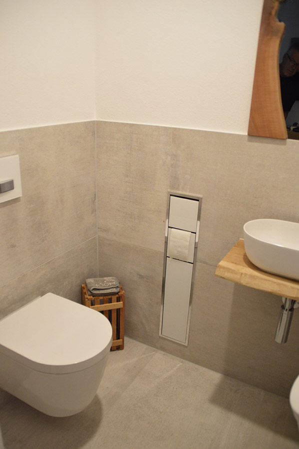 Kleines Bad mit wandhängendem WC, Aufsatzwaschbecken auf Holzplatte und strukturierten Fliesen