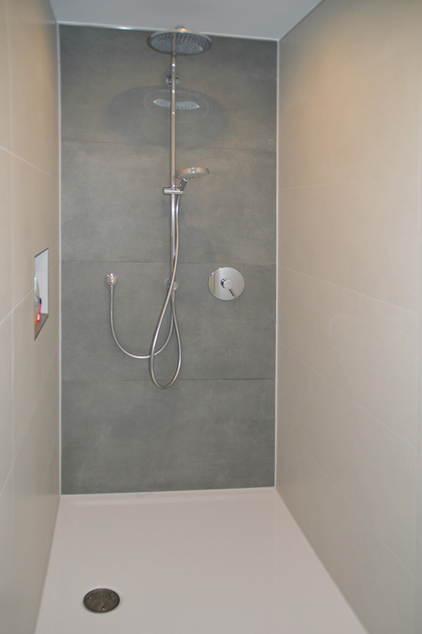 Minimalistische Duschkabine mit Kopfbrause, Handbrause und grauen Großformatfliesen