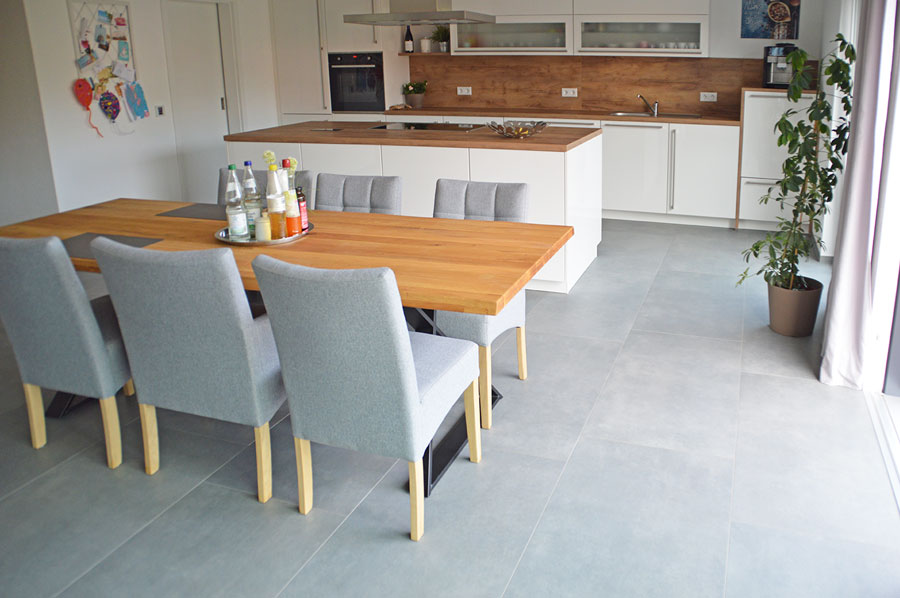 Helle moderne Küche und Essbereich mit grauen Bodenfliesen und weißen Möbeln