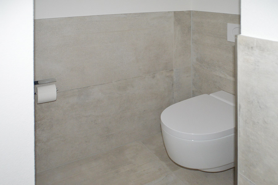 Minimalistisches WC mit hängender Toilette und hellen strukturierten Wandfliesen